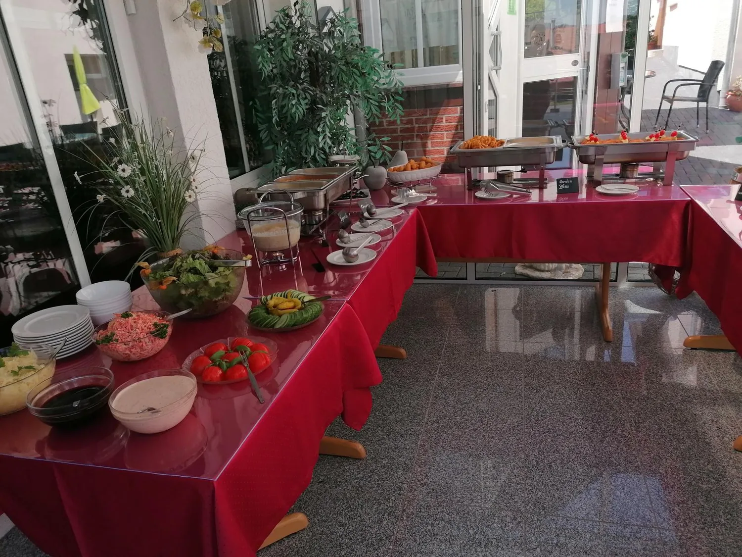 Buffet mit frischen Salaten und Beilagen auf roter Tafel