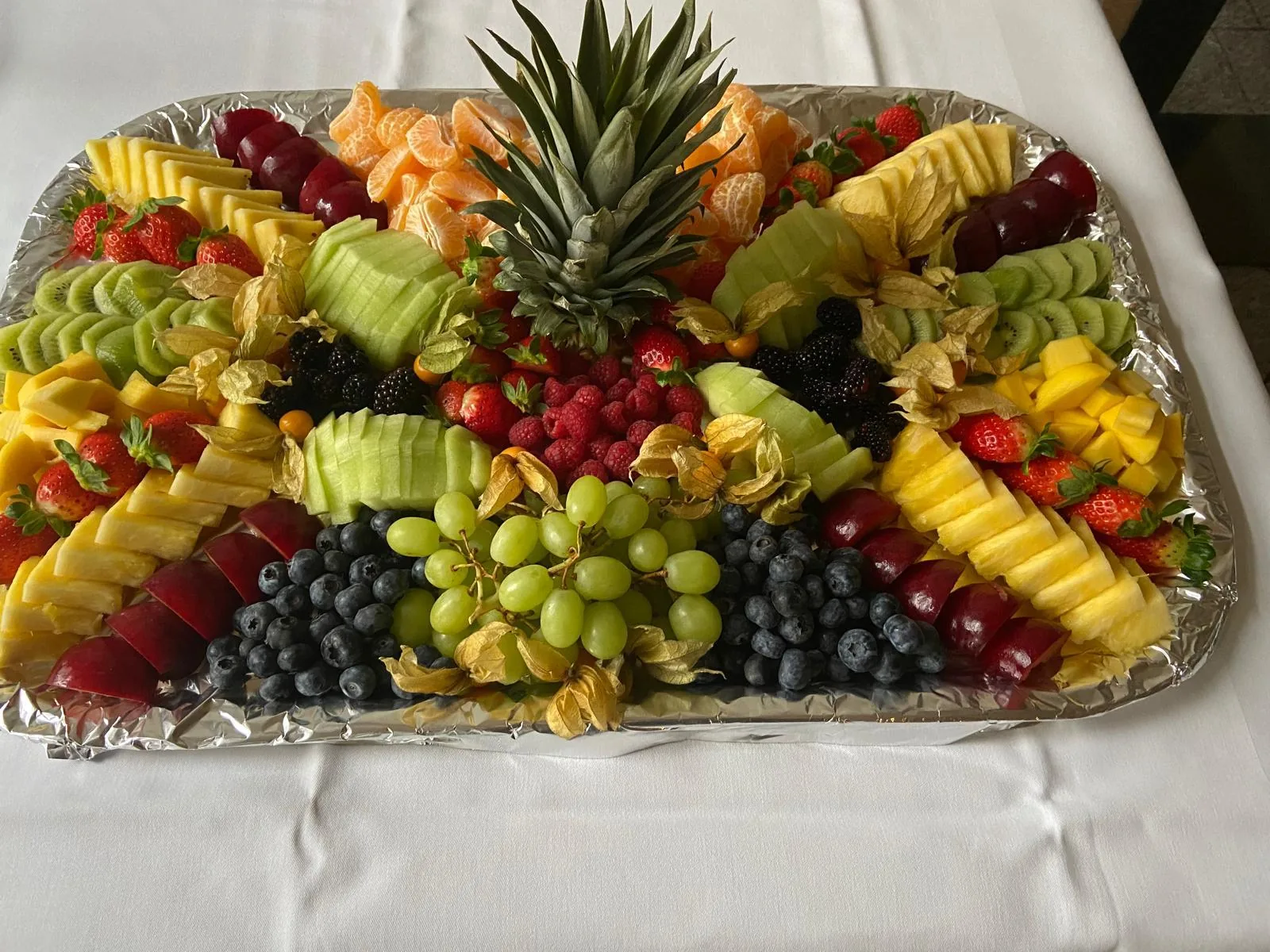 Kunstvoll geschnitzte Obstplatte mit Ananas, Melone, Trauben und Beeren