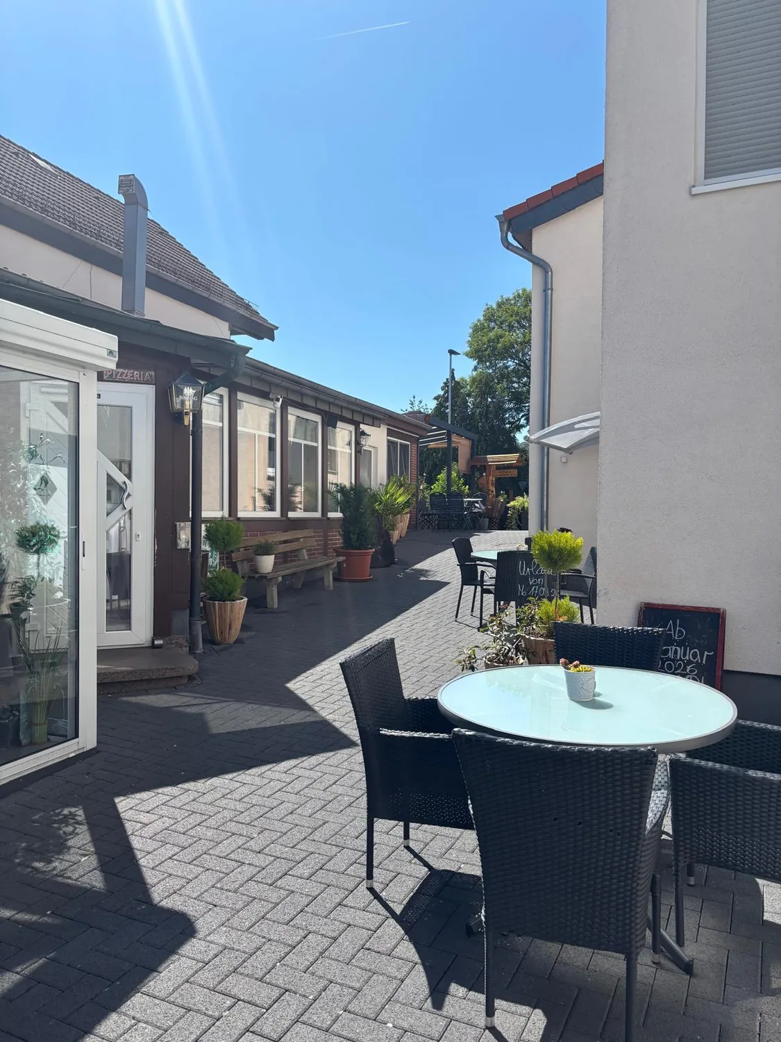 Außenbereich des La Mamma Mia mit Sonnenschirm und Bistrotischen