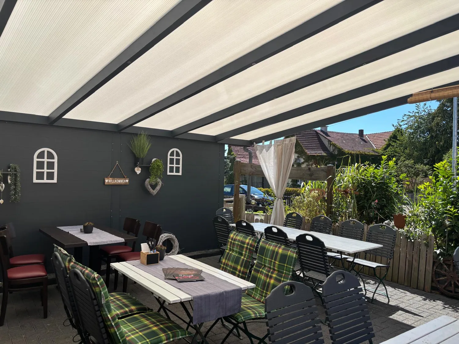 Überdachte Terrasse des La Mamma Mia mit Blick in den Garten